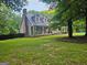 Home exterior with a well-manicured lawn, mature trees, and a covered front porch at 3650 Bay Leaf Dr, Loganville, GA 30052