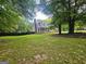 Home exterior with a large lawn, mature trees, a covered front porch and black fencing at 3650 Bay Leaf Dr, Loganville, GA 30052