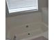 Close-up of a bathtub with white tile surround and window, offering a bright and clean space at 12214 Cypress Way, Fayetteville, GA 30215