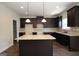 Spacious kitchen features dark cabinetry, granite countertops, an island, and modern recessed lighting at 305 Wheeler Creek Ln # 21, Mcdonough, GA 30252