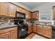 Well-lit kitchen featuring wooden cabinets, granite countertops, stylish backsplash, and modern black appliances at 5260 Sherwood Way, Cumming, GA 30040