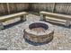 Close up of backyard firepit with stones and wooden benches surrounded by rock bed and wood fence at 2638 Lake Manor Cir, Duluth, GA 30096