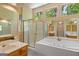 Bright bathroom featuring a soaking tub, glass enclosed shower, and wood vanity at 9276 Fieldstone Ct, Jonesboro, GA 30236