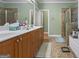 Well-lit bathroom with double vanity, tile floors, and a combination shower and tub at 1154 Ridge Hollow Ln, Lawrenceville, GA 30043