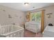 Bedroom featuring two cribs, a rocking chair, and decoratively themed after the Winnie the Pooh stories at 1012 Miss Amber Way, Locust Grove, GA 30248