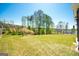 Large grassy backyard with a backdrop of mature trees and a clear blue sky at 44 Mediterranean Ave, Sharpsburg, GA 30277