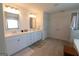 This bright bathroom features double vanity sinks, tile flooring, and a linen closet at 44 Mediterranean Ave, Sharpsburg, GA 30277