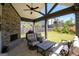 A stone patio with a fireplace, ceiling fan and furniture at 44 Mediterranean Ave, Sharpsburg, GA 30277