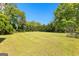 Large, grassy backyard perfect for outdoor activities surrounded by mature trees at 2354 Hamilton St, Hampton, GA 30228