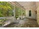 Covered front porch showcasing white railings and a peaceful view of the lush, green yard at 2354 Hamilton St, Hampton, GA 30228