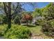 Backyard with mature trees, landscaping, and a white house in the background at 395 Hood Ave, Fayetteville, GA 30214