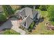 Aerial view of a home with manicured landscaping, stone paved driveways, grey roof and brick patio at 1105 Astoria Ln, Peachtree City, GA 30269