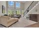 Bright living room with tall windows, comfortable beige seating, and a staircase with an iron railing at 1105 Astoria Ln, Peachtree City, GA 30269