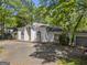 Exterior view of a charming white stucco home with multiple arched windows, side carport, and mature trees at 3985 Randall Mill Nw Rd, Atlanta, GA 30327