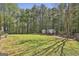 Backyard area with lush lawn and mature trees, features an outbuilding for extra storage at 49 Moss Cts, Palmetto, GA 30268