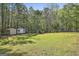 Expansive backyard featuring a shed, fire pit, and wooded area, perfect for outdoor activities at 49 Moss Cts, Palmetto, GA 30268