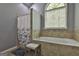 Relaxing bathtub with tiled surround, shower, arched window, and a comfortable stool at 49 Moss Cts, Palmetto, GA 30268