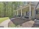 Inviting front porch featuring comfortable seating, decorative columns, and beautiful landscaping with mature trees at 49 Moss Cts, Palmetto, GA 30268