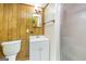 Bathroom features a toilet, sink, wood paneling, and a shower with a glass door at 8289 Lake View Ter, Riverdale, GA 30274