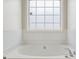 Bright bathroom features a soaking tub beneath a frosted grid window at 115 Stewart Hollow Ln, Covington, GA 30016