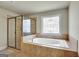 Luxurious bathroom with a glass-enclosed shower and a stylish window above the jetted tub for a spa-like experience at 3705 Royer Ln, Hampton, GA 30228