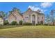 Brick home boasts an arched entryway, a manicured front lawn, and timeless architectural details, perfect for families at 3705 Royer Ln, Hampton, GA 30228