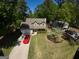 Aerial view of a charming home with a well-manicured lawn, mature trees, and a red sports car in the driveway at 308 Summer Pl, Peachtree City, GA 30269