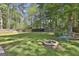 Spacious backyard with lush green grass, fire pit, and a charming butterfly bench surrounded by mature trees at 308 Summer Pl, Peachtree City, GA 30269
