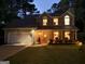 Charming two-story home at twilight features a well-lit entrance, manicured landscaping, and inviting front porch at 308 Summer Pl, Peachtree City, GA 30269