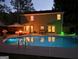 Backyard pool at night with colorful lighting. Featuring outdoor seating and lush landscaping at 308 Summer Pl, Peachtree City, GA 30269