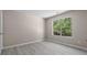 Bright bedroom with modern gray floors and a window offering a view of the lush greenery outside at 5882 Trent Walk Dr, Lithonia, GA 30038