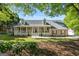 Charming single-Gathering home boasts a welcoming front porch, lush landscaping, and red shutters at 423 Bear Creek Trl, Hampton, GA 30228