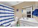 Standard bathroom with white vanity, toilet, and shower/tub combo with blue and white striped shower curtain at 122 Ardenlee Dr, Peachtree City, GA 30269