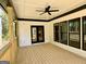Covered outdoor patio with wood floors, ceiling fan and black trimmed windows at 409 Saint Surrey Way, Ellenwood, GA 30294