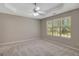 Spacious bedroom with a ceiling fan, neutral carpet, large window, and tray ceiling at 8032 Highland Pkwy, Fairburn, GA 30213