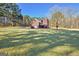 View of the back of the home highlighting a lush green lawn and beautiful architectural details with mature trees at 671 Ellison Rd, Tyrone, GA 30290