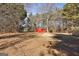Backyard showing a red storage shed and large trees, with a mix of grass and leaves on the ground at 113 Elmwood Dr, Hampton, GA 30228