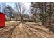 Backyard showing a red storage shed and large trees, with a mix of grass and leaves on the ground at 113 Elmwood Dr, Hampton, GA 30228