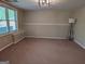Living room features neutral carpeting, a bright window, and a sleek floor lamp at 1581 Shetland Pony Nw Ct, Suwanee, GA 30024