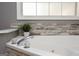 Bathroom close-up on a large soaking tub with stone tile surround and a picture window at 1252 Heritage Dr, Villa Rica, GA 30180