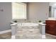 Bathroom close-up on a large soaking tub with stone tile surround, perfect for relaxation at 1252 Heritage Dr, Villa Rica, GA 30180