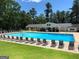 A large community pool with lounge chairs, surrounded by trees and lush green lawn at 1252 Heritage Dr, Villa Rica, GA 30180