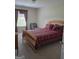 Bedroom featuring a wood-framed bed with red patterned bedding and natural light at 35 Charleston Ln, Covington, GA 30016