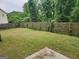 The backyard is spacious and surrounded by a wooden fence and green trees at 2337 Carousel Park Dr, Morrow, GA 30260