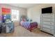 This bedroom features a colorful comforter, a window that lets in natural light, and a stylish silver dresser at 11755 Lovejoy Crossing Blvd, Hampton, GA 30228