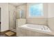 Well-lit bathroom with separate shower and bathtub, featuring tile accents and a patterned window for privacy at 790 Riverwood Pass, Dallas, GA 30157