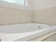 Close-up of the pristine white bathtub, showcasing the tile surround and stylish fixtures in the bathroom at 790 Riverwood Pass, Dallas, GA 30157