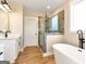 Bright bathroom with a soaking tub and glass shower featuring modern fixtures and wood-look tile at 4711 H D Atha Rd, Covington, GA 30014