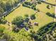 Aerial view of a large property with a home, barn, pool, and vast green fields at 13819 Woolsey Rd, Hampton, GA 30228