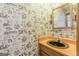 Unique powder room featuring novelty wallpaper, a vintage sink, and a large mirror at 13819 Woolsey Rd, Hampton, GA 30228